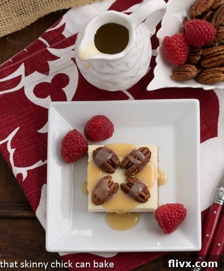 Overhead view of Caramel Pecan Cheesecake Bars on a square white plate garnished with raspberries.