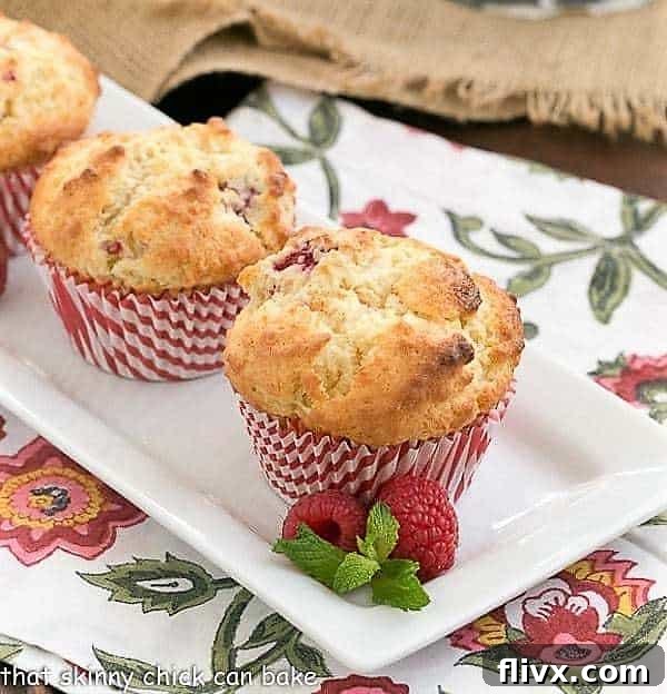 Spectacular Raspberry White Chocolate Muffins on a white rectangular platter, showcasing their golden tops and visible berries.