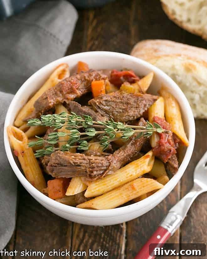 Beef Ragu with penne pasta - a hearty and flavorful twist on a classic comfort dish. Rich Beef Ragu with penne pasta served in a white bowl, accompanied by a slice of crusty bread and a fork, ready to be enjoyed.