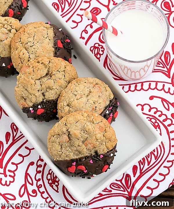 An overhead shot of several Big Dipper Oatmeal Butterscotch Cookies arranged on a festive red and white checkered napkin, accompanied by a refreshing glass of milk.