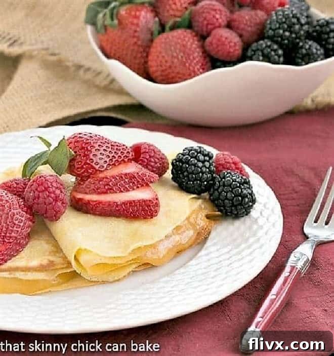 Butter and Rum Crêpes filled with vibrant lemon curd and garnished with an array of fresh berries, elegantly presented.