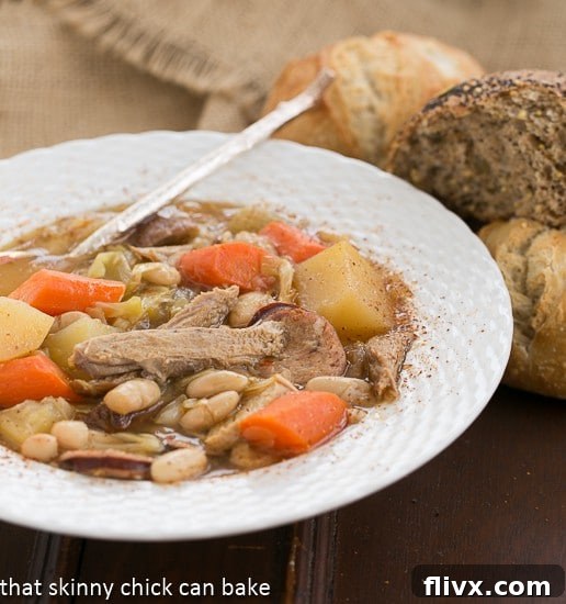French Garbure Stew in a white soup bowl, garnished with fresh herbs.