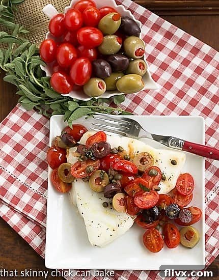 Sea Bass with Tomatoes, Olives and Capers on white plate viewed from above.