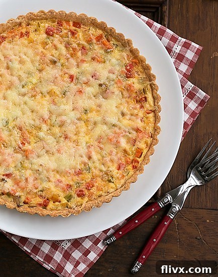 An overhead view of a perfectly baked Quiche Maraîchère, showcasing its golden-brown top, melted Gruyère, and the colorful medley of vegetables beneath the custard.