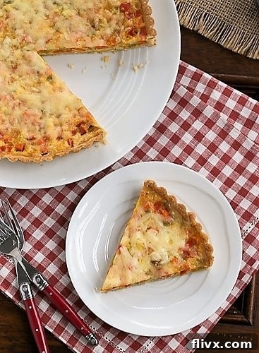 A slice of Quiche Maraîchère carefully removed from the serving plate, revealing the layers of rich custard, tender vegetables, and golden crust.