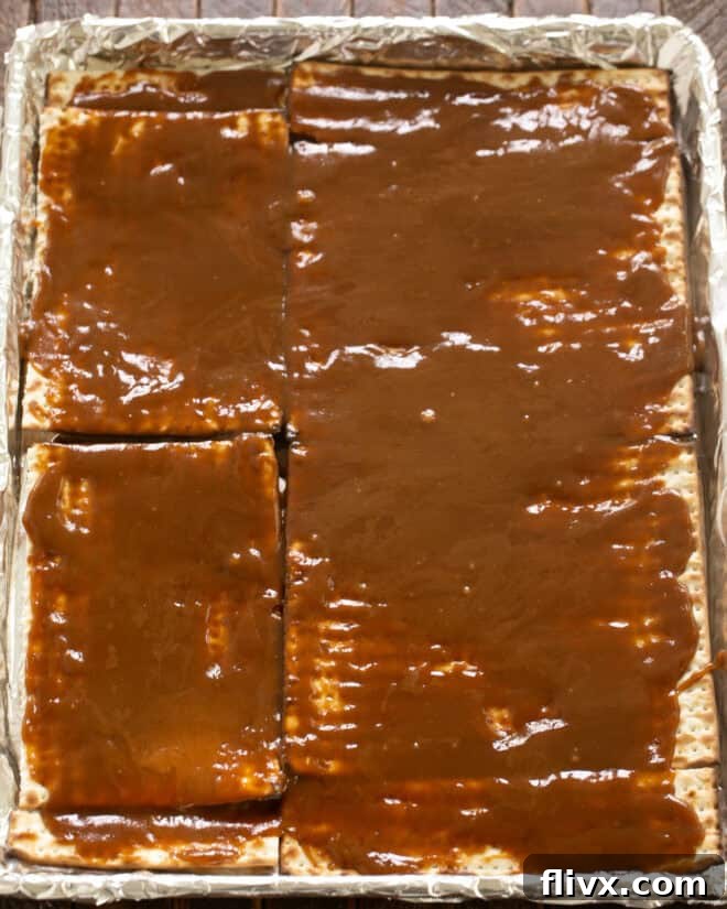 Pour the hot caramel mixture evenly over the matzoh, ensuring every piece is coated.