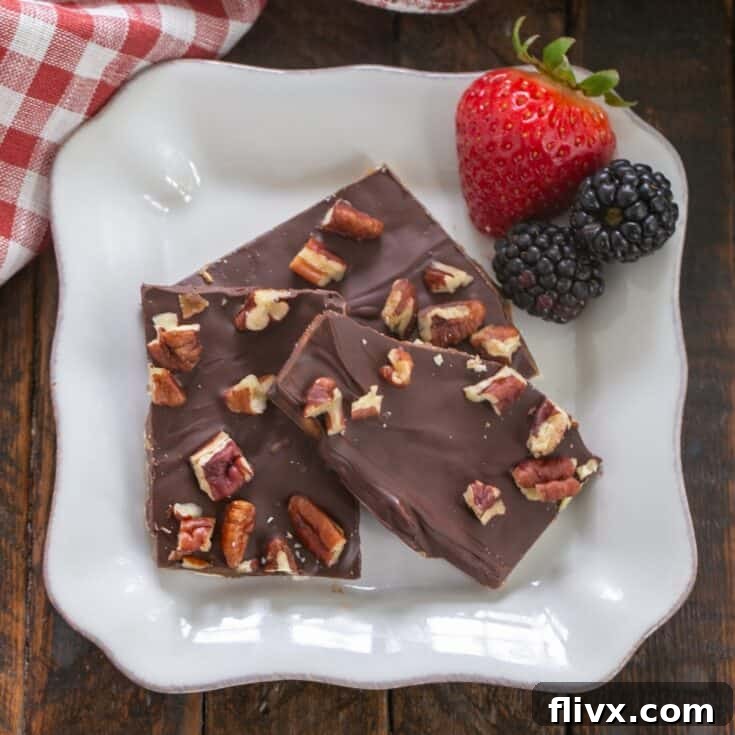 Matzo crack on a square white plate with berries, showcasing its crisp texture and chocolate topping.