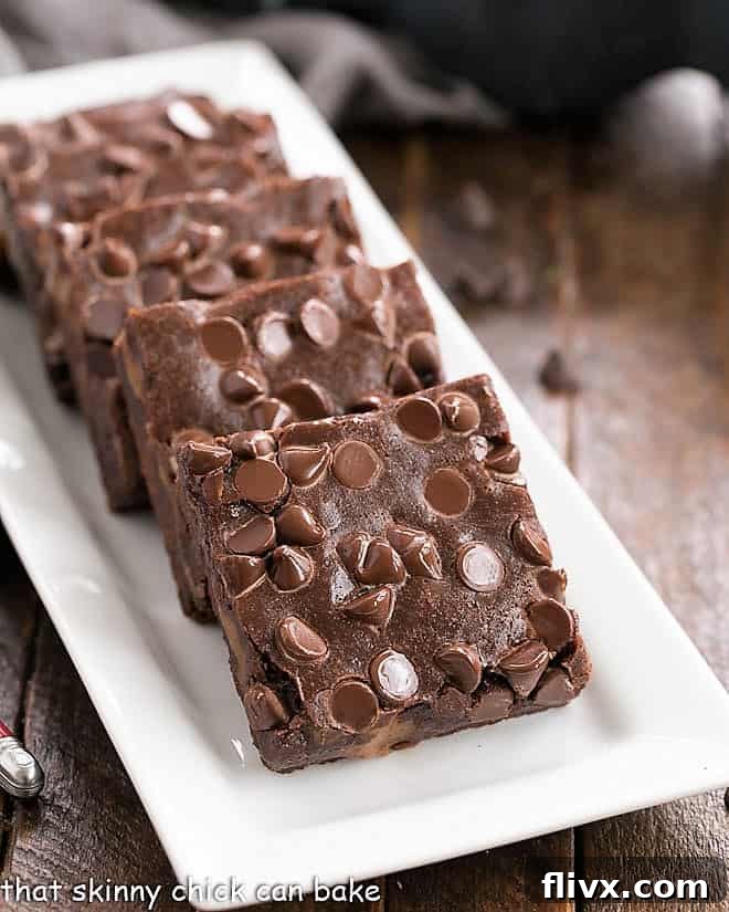 A front view of a bountiful platter filled with delectable Chocolate Caramel Brownies, elegantly arranged on a pristine white serving tray. The rich caramel swirls atop the chocolate base promise a luxurious and indulgent treat.