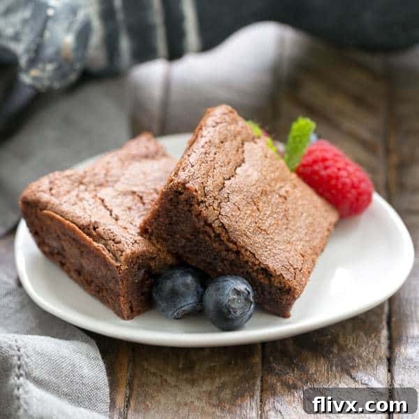 Delicious Simple Fudgy Brownies elegantly arranged on an oval white dish, beautifully garnished with an assortment of fresh, vibrant berries, creating a delightful contrast of colors and flavors.