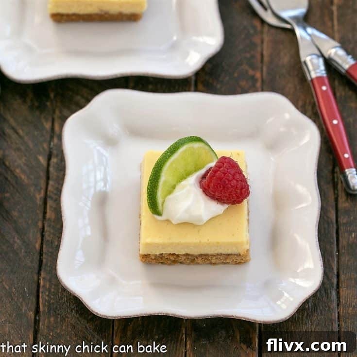 Overhead view of a key lime pie bar with a dollop of whipped cream, slice of lime and raspberry to garnish