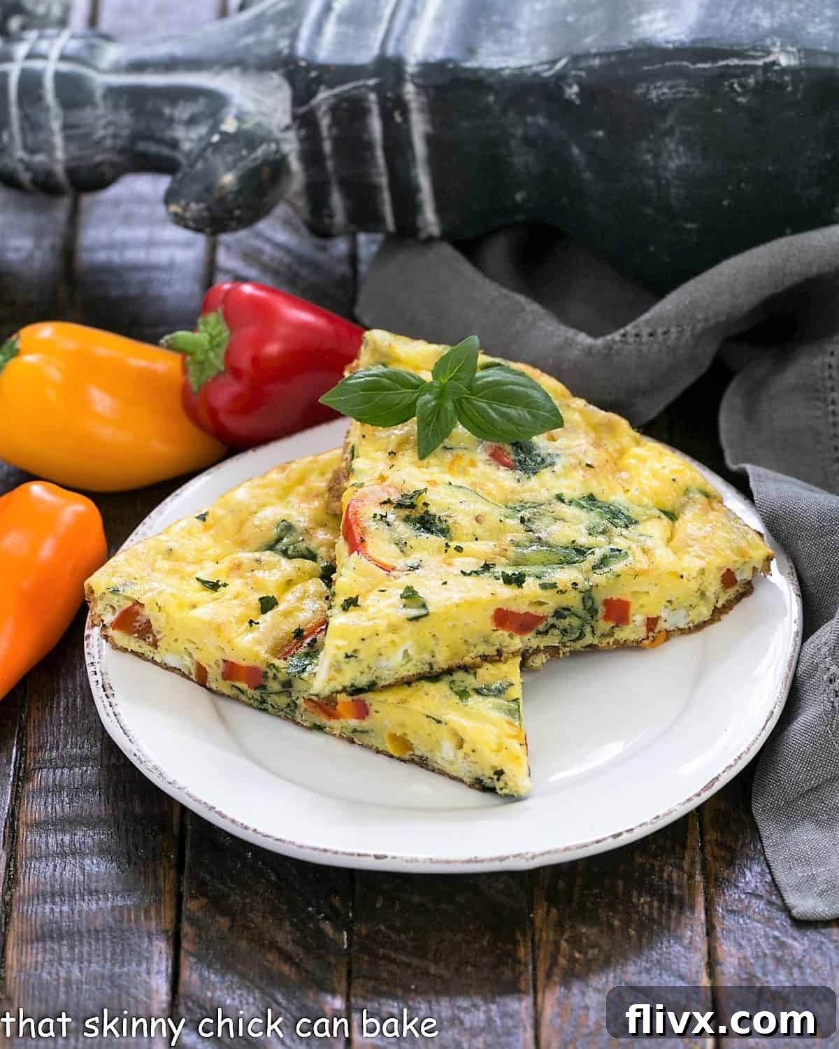 Two slices of vibrant Spinach Bell Pepper Frittata beautifully arranged on a white plate, with fresh mini bell peppers scattered in the background, highlighting its fresh ingredients and delicious appeal.
