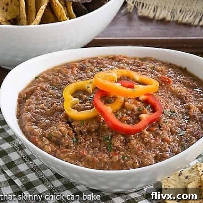 Smoky Black Bean Dip in a white bowl topped with fresh bell pepper rings and cilantro.