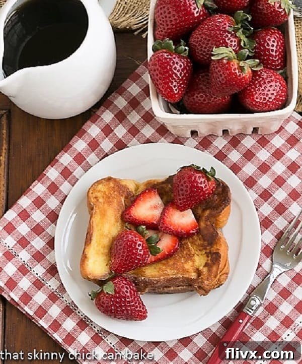 Strawberry Mascarpone Stuffed French Toast overhead view with a drizzle of syrup and a basket of fresh strawberries on a rustic wooden board.