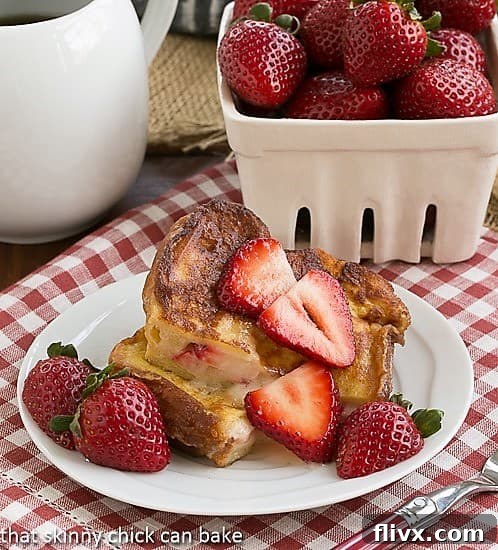 Strawberry Mascarpone Stuffed French Toast cut in half and served topped with sliced strawberries and a sprig of mint.