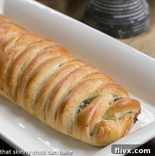 An unbaked Spinach and Onion Braid, beautifully formed on a white ceramic tray, ready for the oven.