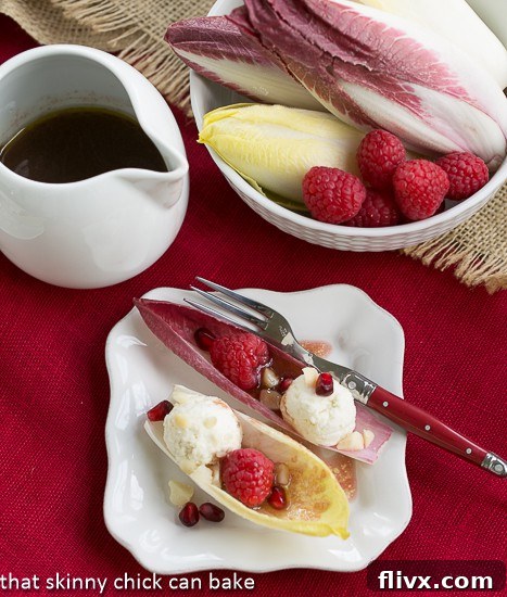 Endive Cups with Blue Cheese, Raspberries and Macadamia Nuts on a square white plate with a drizzle of vinaigrette, ready to serve.