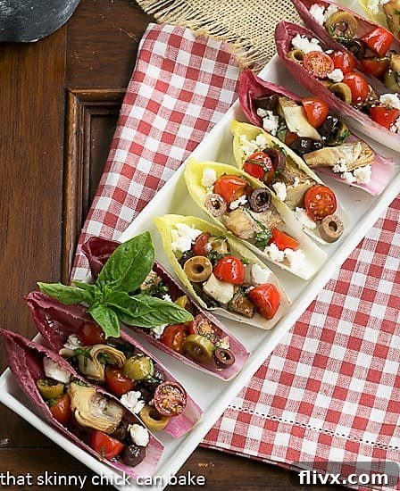 A tray of Mediterranean Endive Boats arranged neatly on a festive red and white checked napkin, ready for serving guests.