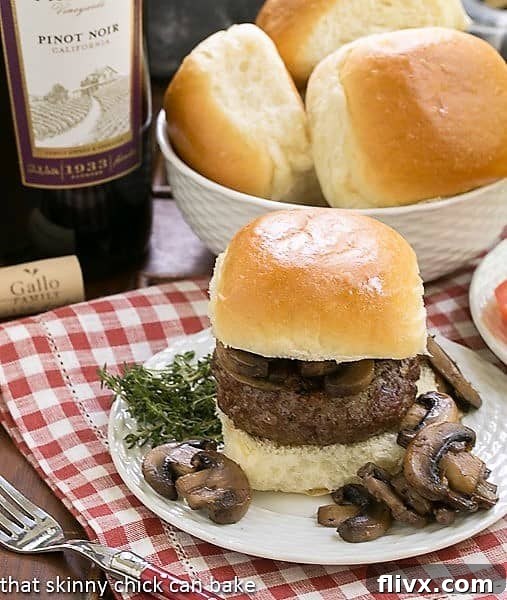 Mushroom Topped Pinot Noir Burgers on a white plate with mushrooms and herbs, ready to be enjoyed.