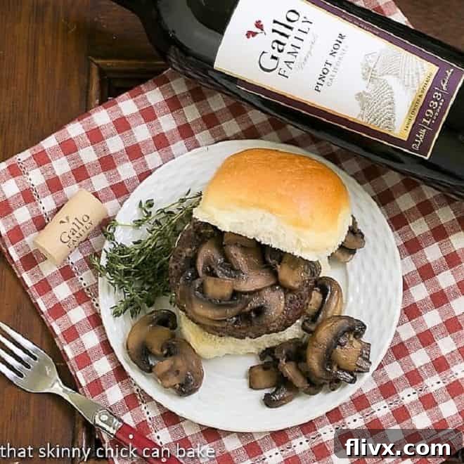 Overhead view of two Mushroom Topped Pinot Noir Burgers on a plate with fresh greens.
