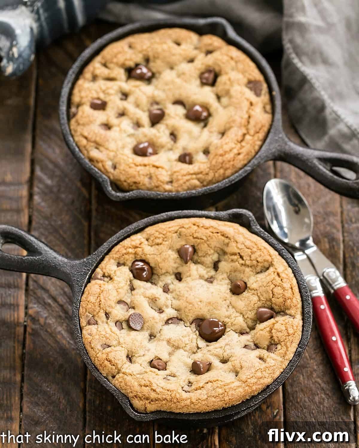 Overhead view of two golden-brown chocolate chip pizookies in cast iron skillets, before topping with ice cream.