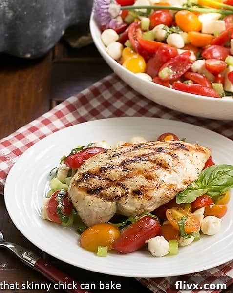 Grilled chicken breast over a Caprese Salad with Chicken, beautifully plated for a gourmet meal.