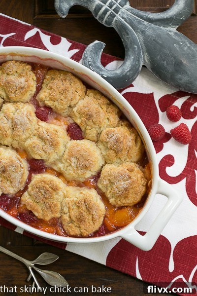 An inviting overhead view of a golden-brown Fruit Cobbler, nestled in a pristine white, oval casserole dish, ready to be served.