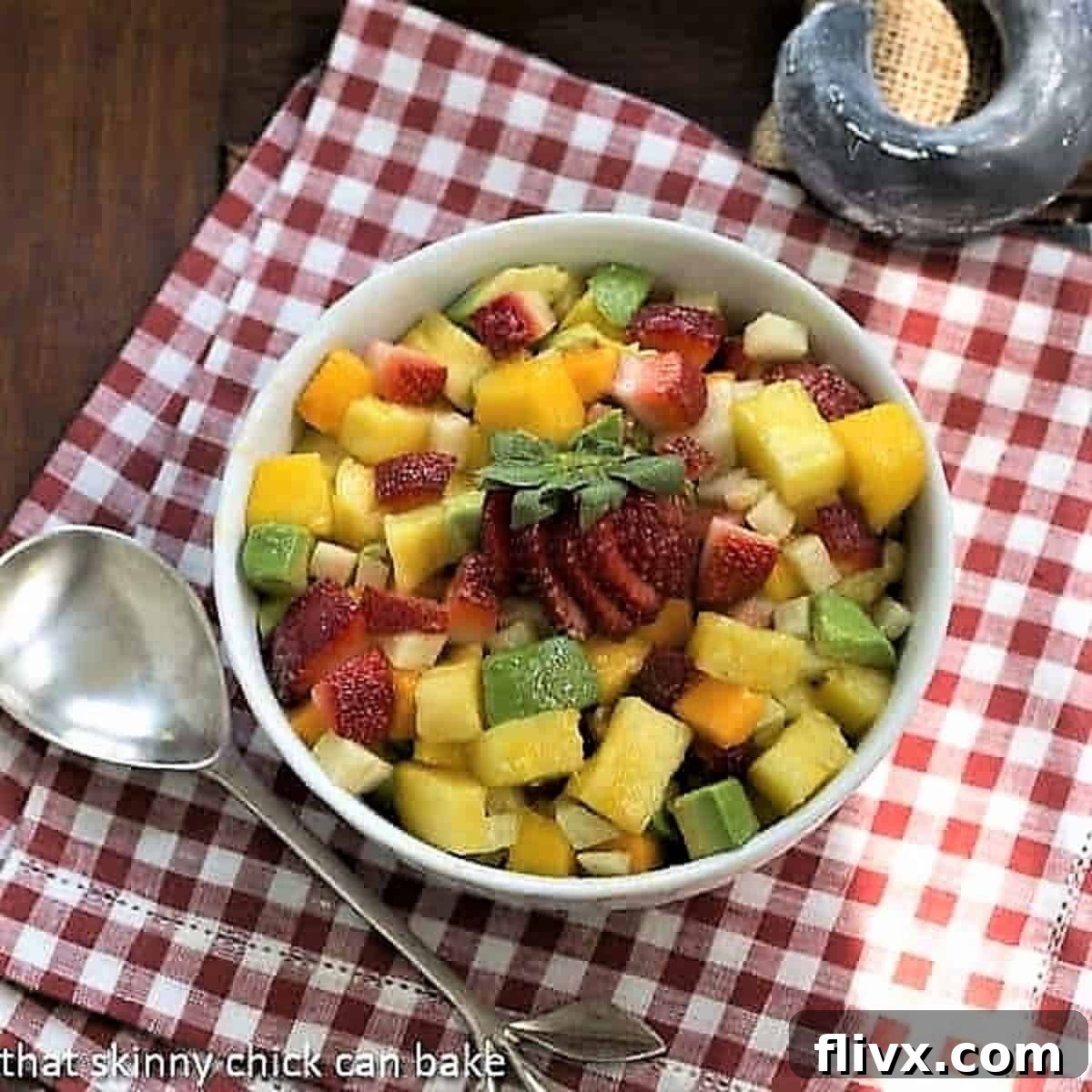 Mango Strawberry Avocado Salad in a white bowl on a red and white checked napkin.