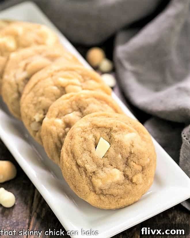 Freshly baked White Chocolate Macadamia Nut Cookies displayed on a pristine white ceramic tray, highlighting their golden edges and creamy white chocolate chunks.