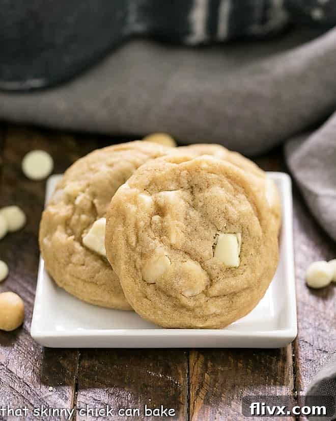 Close-up shot of baked White Chocolate Macadamia Nut Cookies arranged on a square white plate, showing off their texture and melted chocolate.