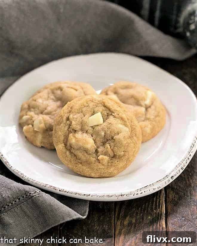 A trio of perfectly baked White Chocolate Macadamia Nut Cookies on a clean white plate, ready to be enjoyed.