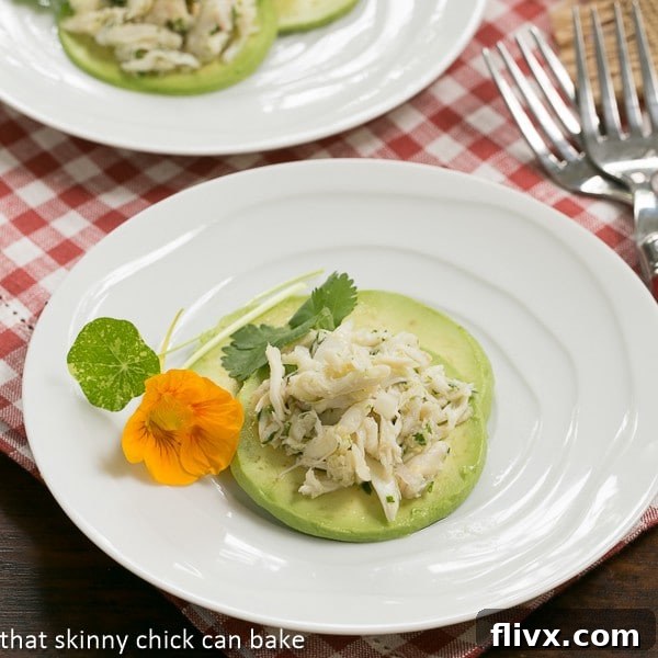 Close-up of Crab Avocado Ravioli slices arranged artfully on a white plate, garnished with a delicate edible flower, emphasizing its gourmet appeal.
