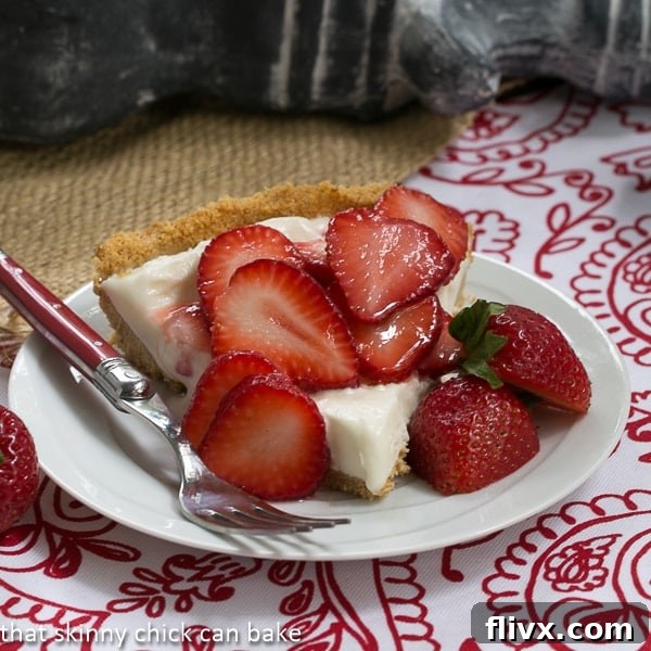 A slice of Strawberry Cheesecake Ice Cream Pie with a graham cracker crust and fresh strawberries on top