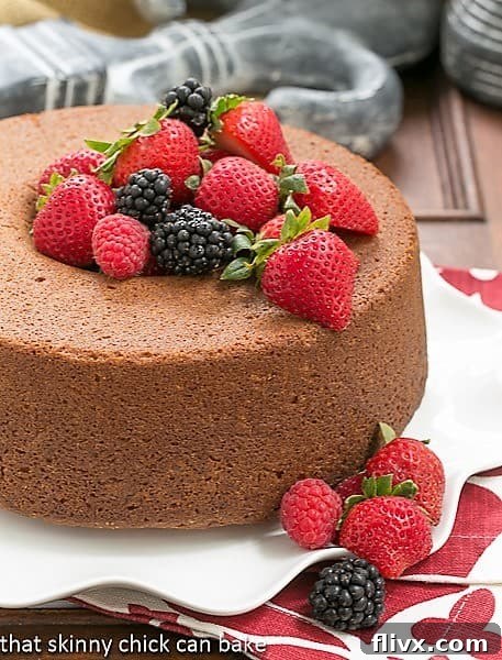 Vanilla Pound Cake - Perfect dessert topped with summer berries or any seasonal topping Whole Vanilla Pound Cake on a white ruffled plate, beautifully presented with a generous topping of fresh berries.