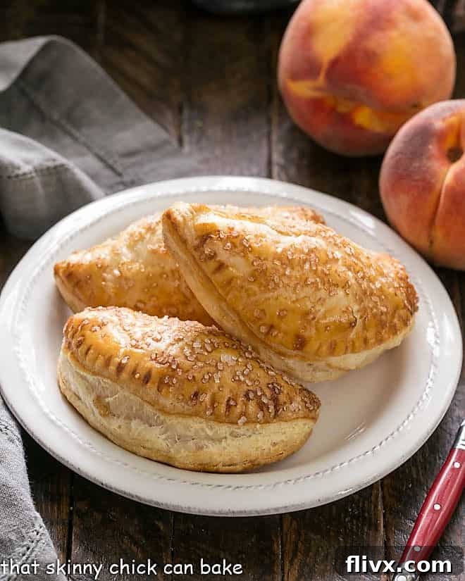 Peach Hand pies on a round white plate with a red handled fork