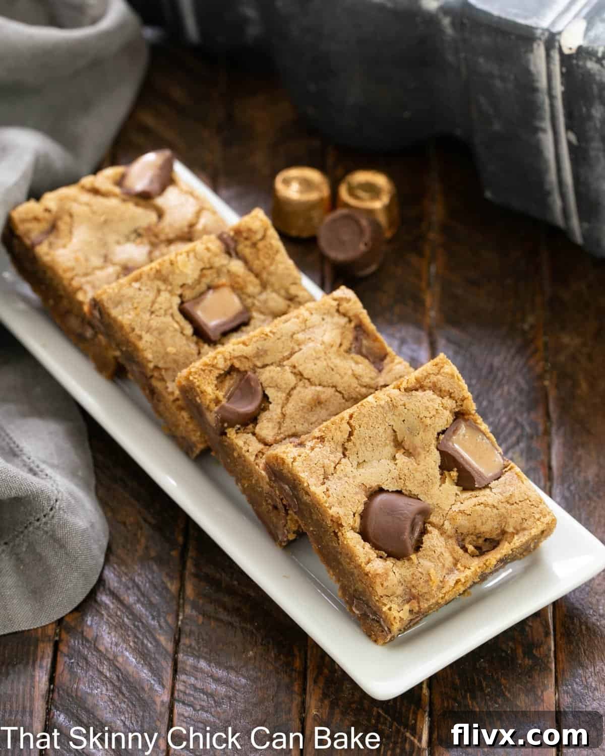 Four Biscoff Rolo Bars artfully arranged on a pristine white ceramic tray, showcasing their tempting layers of cookie butter base and melted Rolo candies.