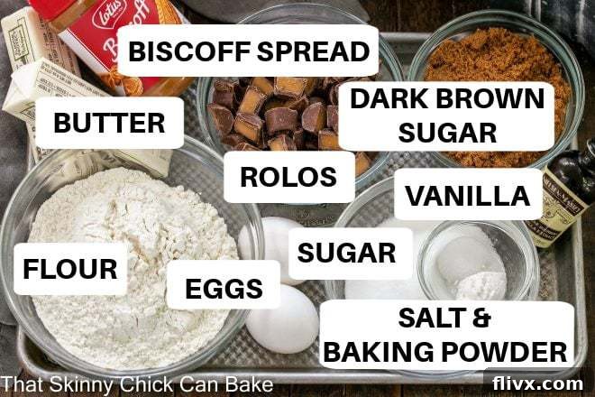 Ingredients for Biscoff Rolo Bars neatly laid out on a rustic metal tray, with labels indicating butter, sugars, eggs, Biscoff spread, flour, baking powder, salt, and Rolo candies.