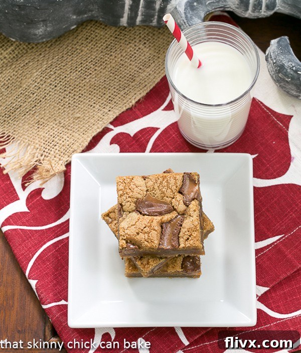 A charming image of Biscoff Rolo Bars stacked invitingly on a square white plate, accompanied by a refreshing glass of milk, highlighting their perfect pairing.