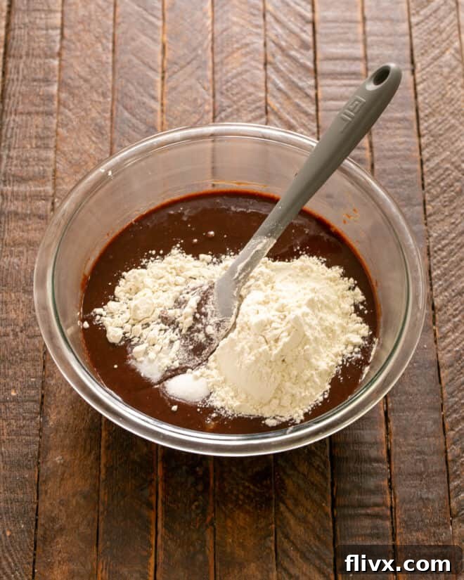 Flour and salt being gently stirred into the brownie batter, ensuring perfect texture.