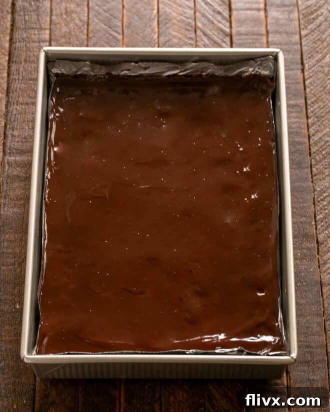 Silky smooth ganache being spread over cooled truffle brownies, creating a perfect finish.