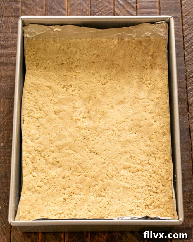 Shortbread crust evenly pressed into the bottom of a prepared baking pan, forming the base of the truffle brownies.