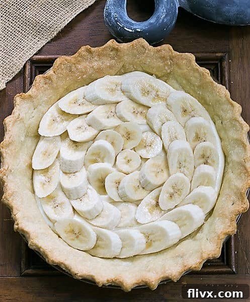Banana Cream Cheesecake Pie with a perfectly baked crust and visible layers of fresh banana slices beneath the creamy filling.