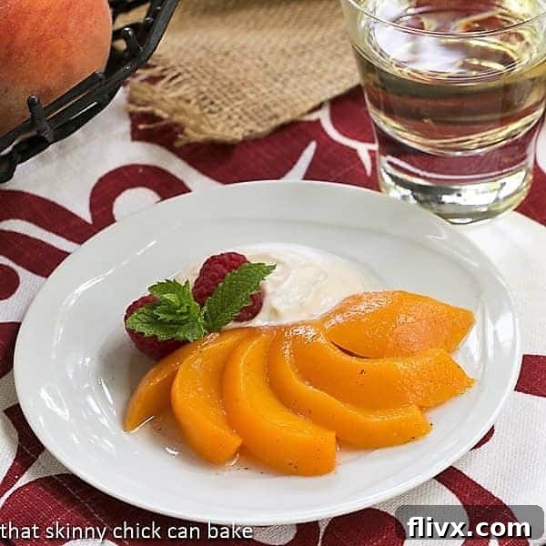 Poached peach fanned out on a white dessert plate, garnished with mascarpone cream and berries.