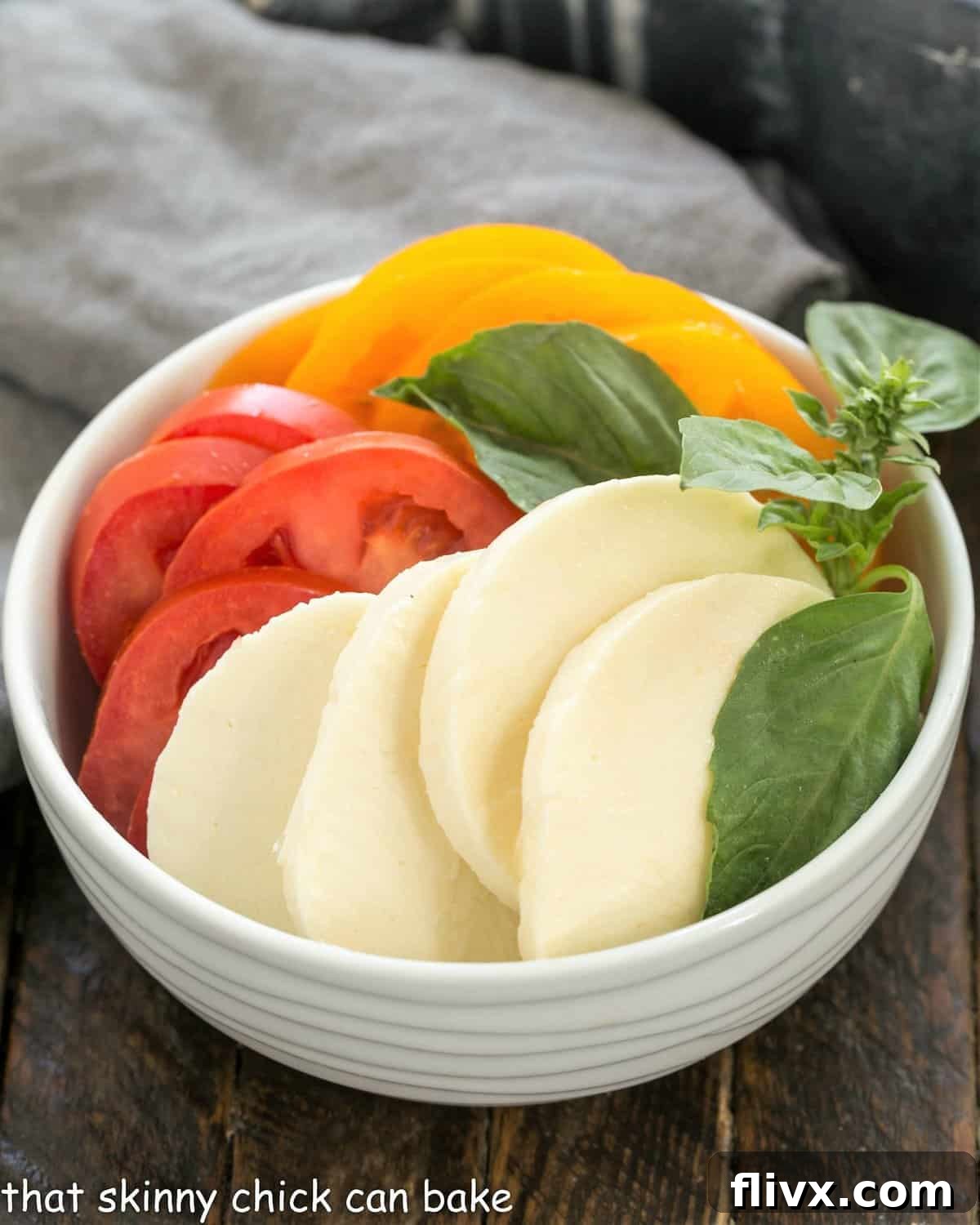 Homemade Pizza Margherita toppings sliced in a white bowl, featuring fresh mozzarella, tomatoes, and basil.