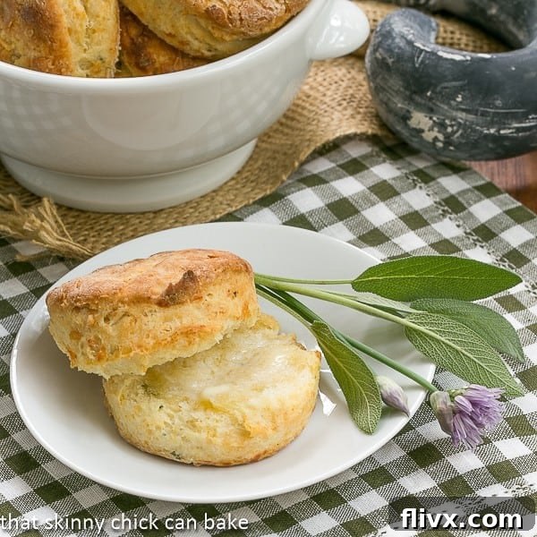 Herbed Buttermilk Biscuits on a white plate with sage and chives, showcasing their golden-brown tops and flaky texture.