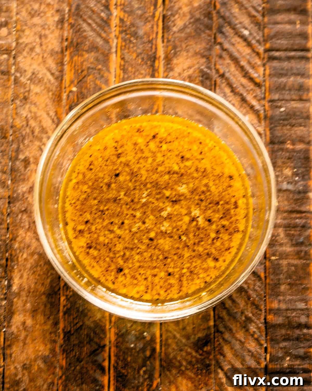 A beautifully prepared chicken marinade, a harmonious blend of mustard, garlic, and lime, resting invitingly in a clear glass bowl, ready for the chicken.