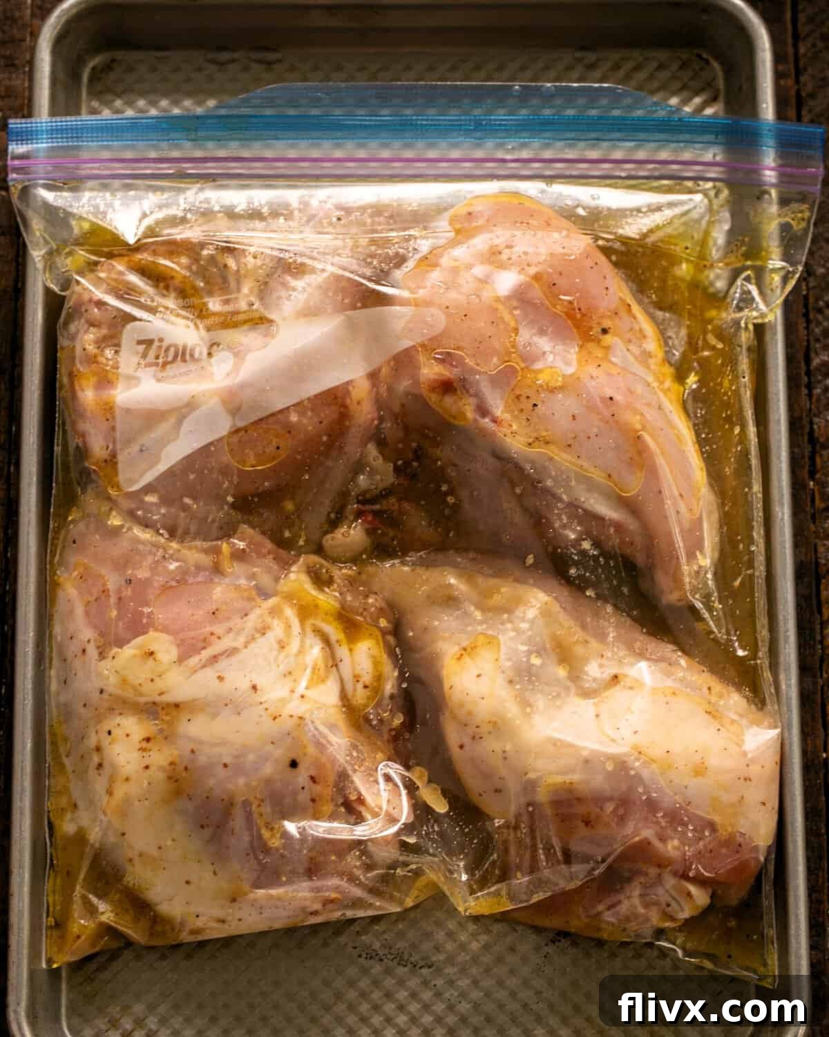 Chicken breasts perfectly coated in a vibrant marinade, sealed securely within a Ziploc bag, resting on a sheet pan for easy refrigeration.