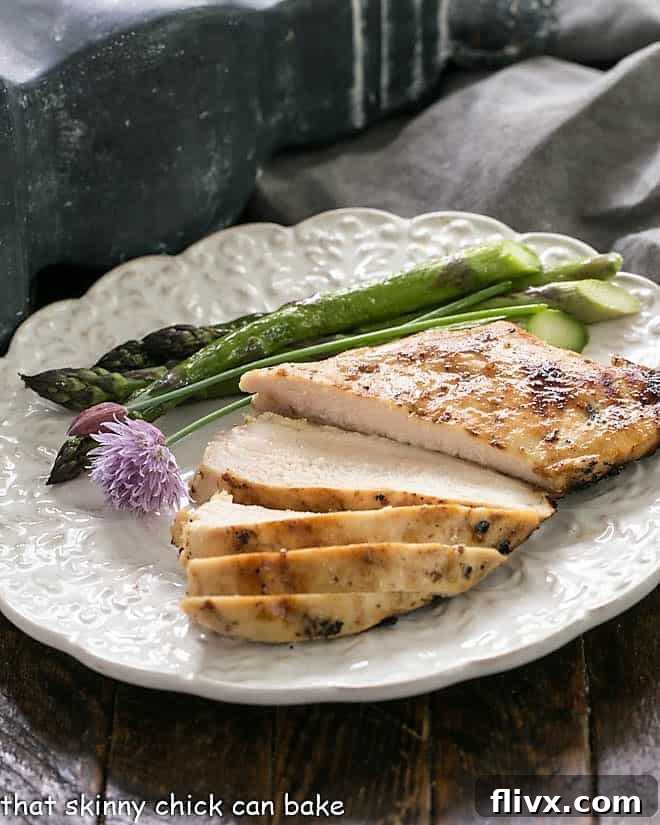 A sliced chicken breast on a white dinner plate with asparagus