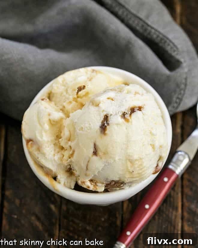 Overhead view of a white bowl of Vanilla Caramel Swirl Ice Cream with a red handle spoon, showing the smooth texture and rich color.