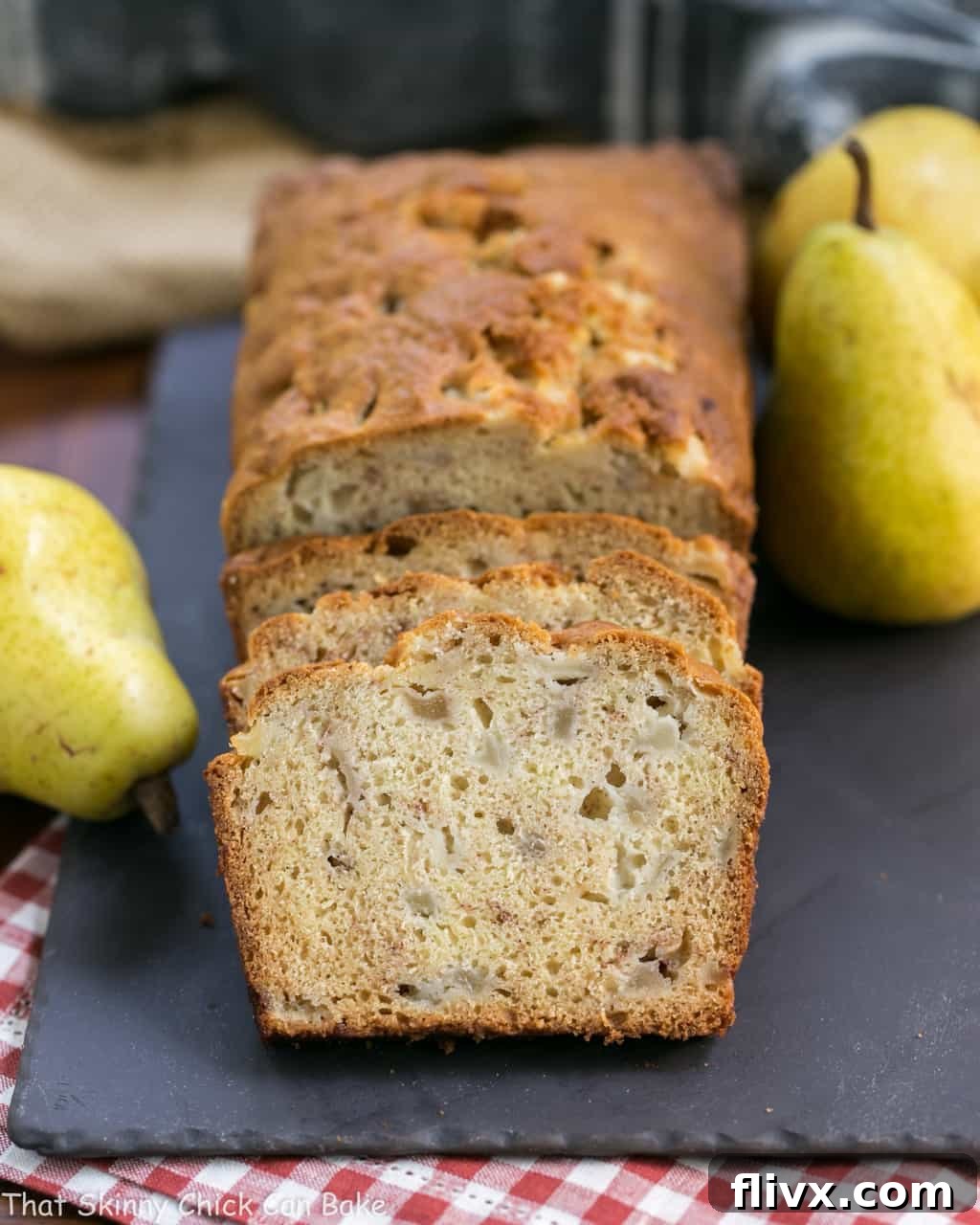Sliced Sour Cream Pear Bread with whole pears on a slate tray, elegantly presented.