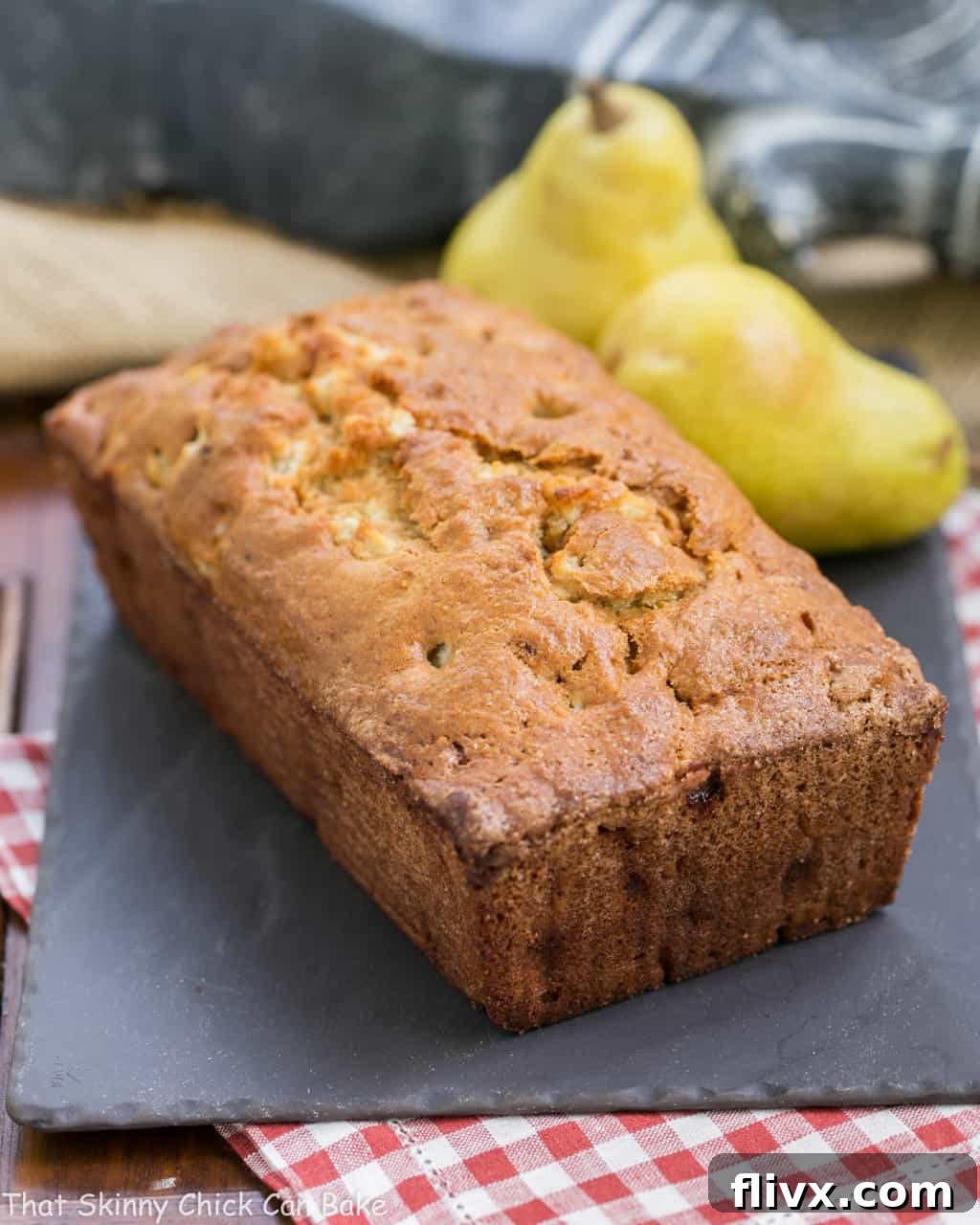 A beautifully baked loaf of Sour Cream Pear Bread on a slate board, ready to be sliced.